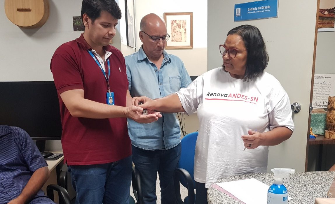 Vice-presidenta da Adufms, Mariuza Guimarães, entrega chave para o diretor substituto do CPan, Fernando Thiago; ao fundo, Ronny Moraes, diretor da Adufms Pantanal.